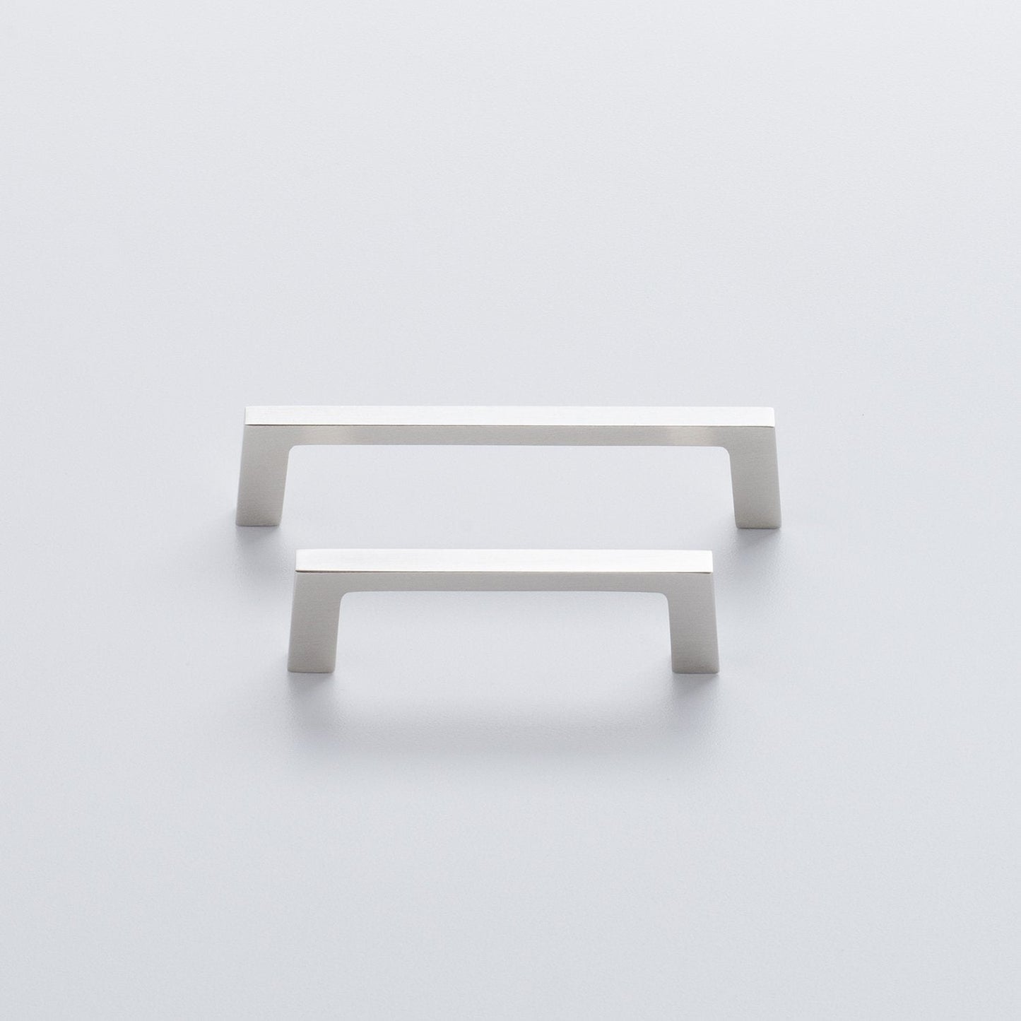 Front view of two Greenwood Pull drawer handles showcasing thin profiles and splayed stems on a light background