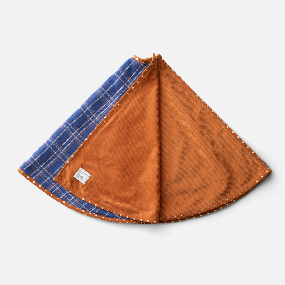 Top view of Haberdasher’s Tree Skirt showcasing cobalt plaid, rust corduroy, and printed trim on a white background