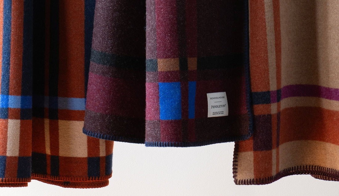 Close-up of plaid blankets showcasing multicolor woven patterns and stitched edges against a white background