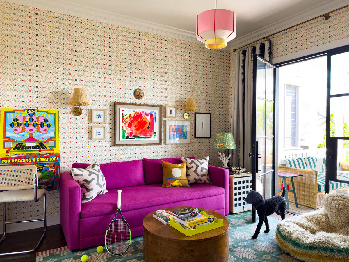 Colorful living room with a magenta sofa, patterned walls, dog, and tennis racket