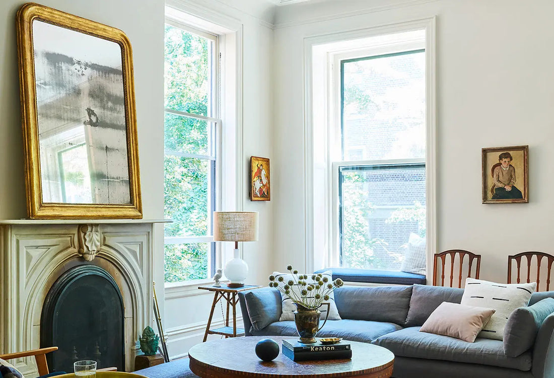 Bright living room with a fireplace, blue sofa, tall windows, and round coffee table