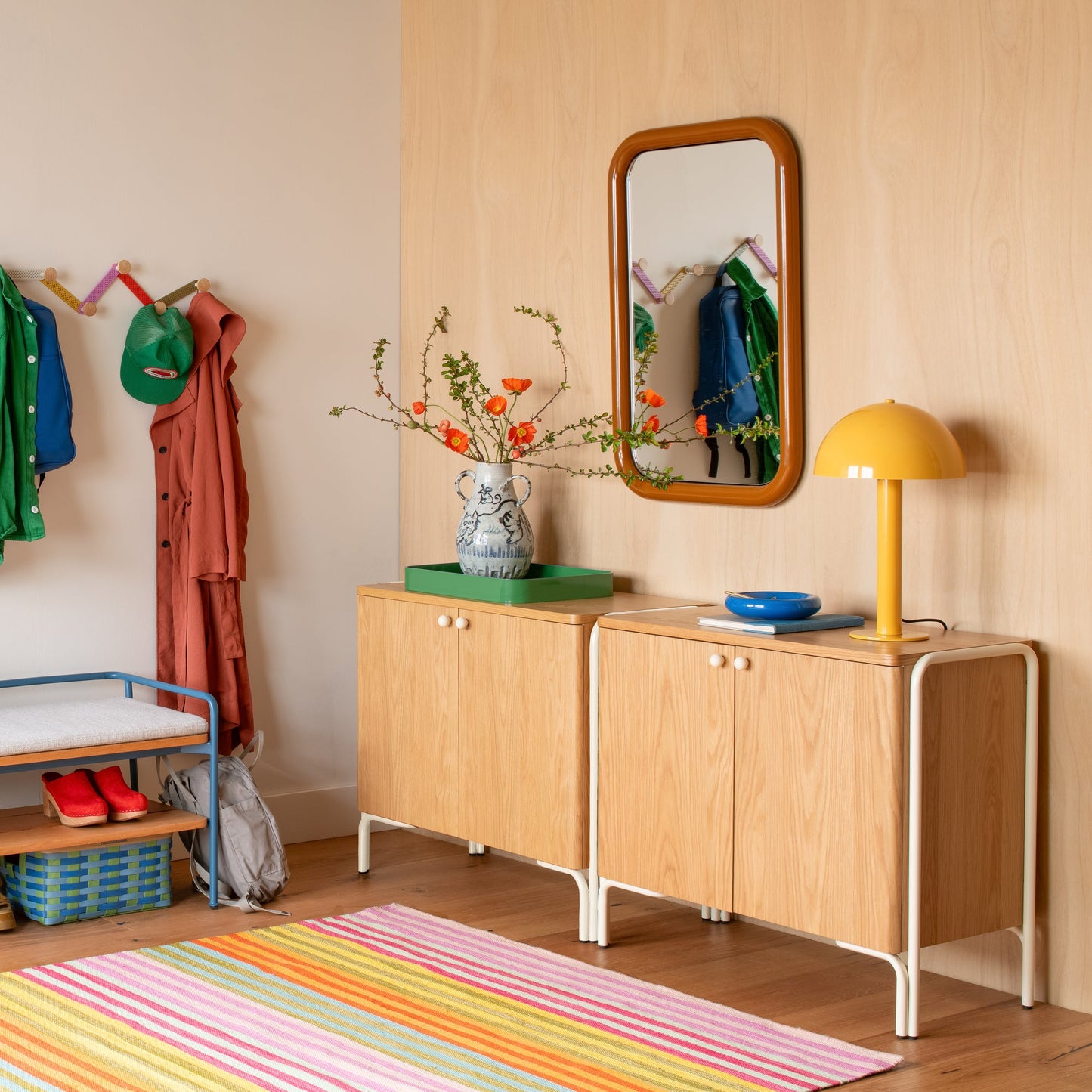 Front view of Forma Cabinet showing oak-veneered doors and white steel legs in a styled entryway