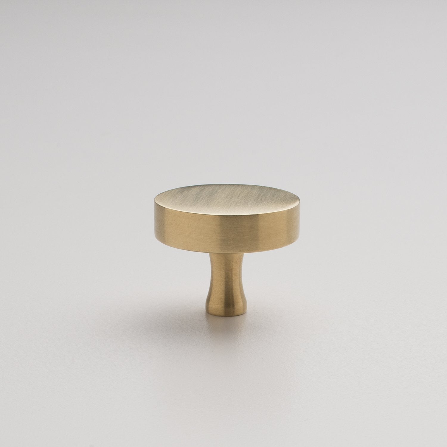 Front view of the natural brass Riverwood Knob showcasing its flat finish and fluted neck on a light background