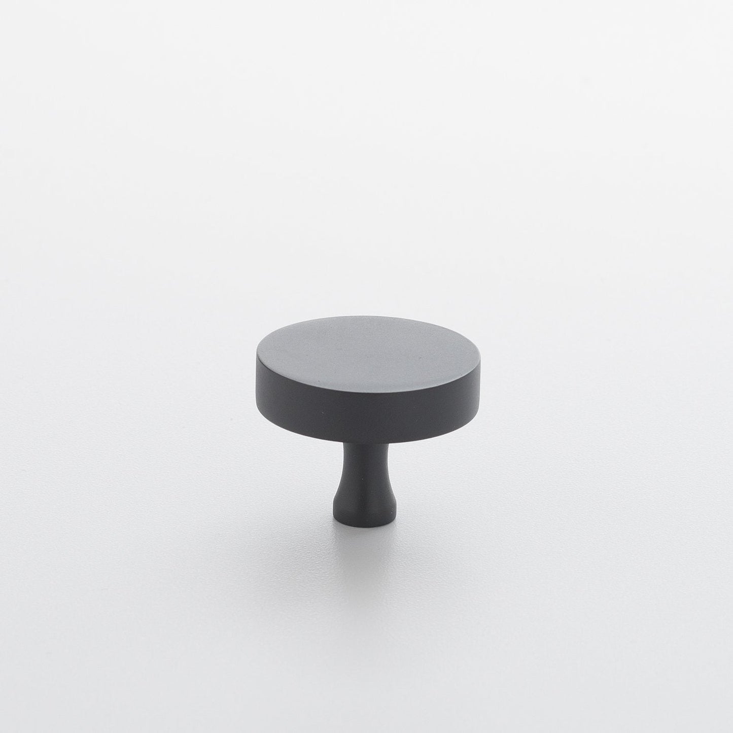 Elevated front view of Riverwood Knob in True Black showcasing its flat finish and fluted neck on a light gray background