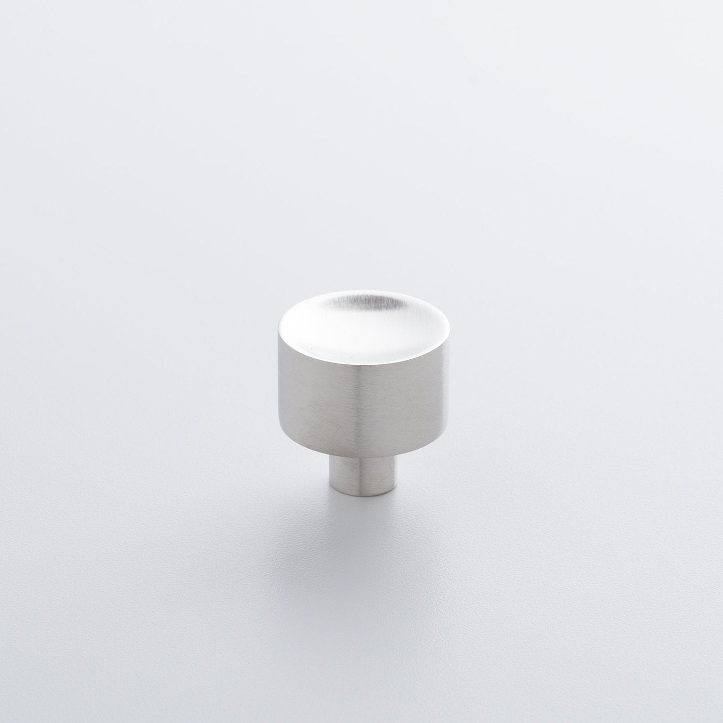 Angled view of Mid Century Knob showcasing a brushed silver finish with a light gray background