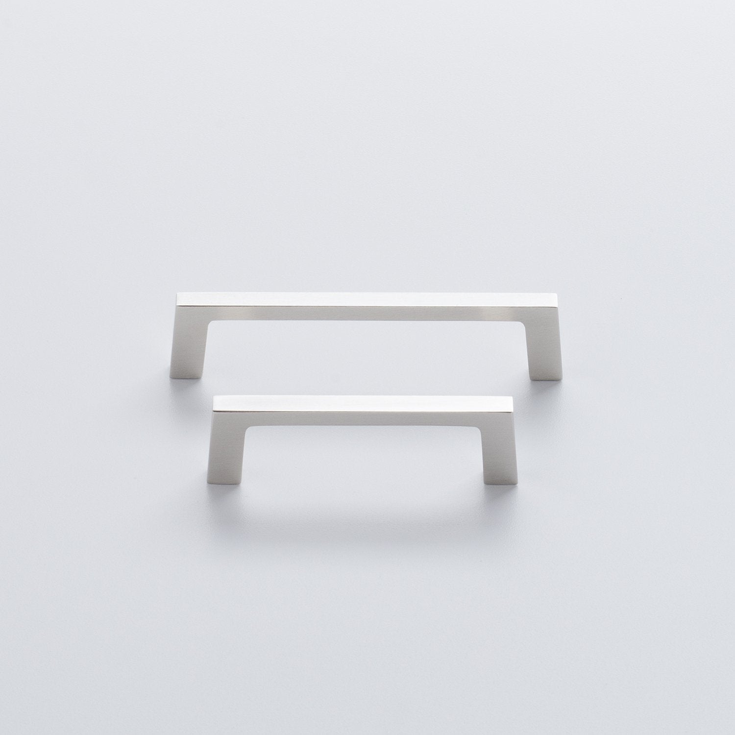 Front view of two Greenwood Pull drawer handles showcasing thin profiles and splayed stems on a light background