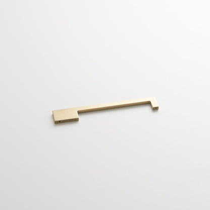 Angled view of the Alberta Pull showcasing its thin, asymmetrical natural brass design on a white background