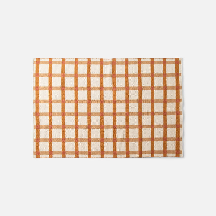 Top edge of Plaid Wool Reversible Rug showcasing orange-and-tan plaid handwoven wool on white background