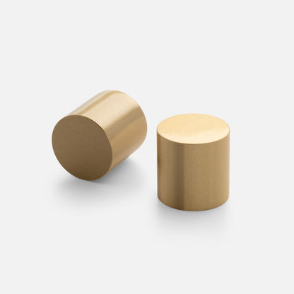 Multiple views of Cove Knob showcasing its cylindrical gold tone finish on a light background