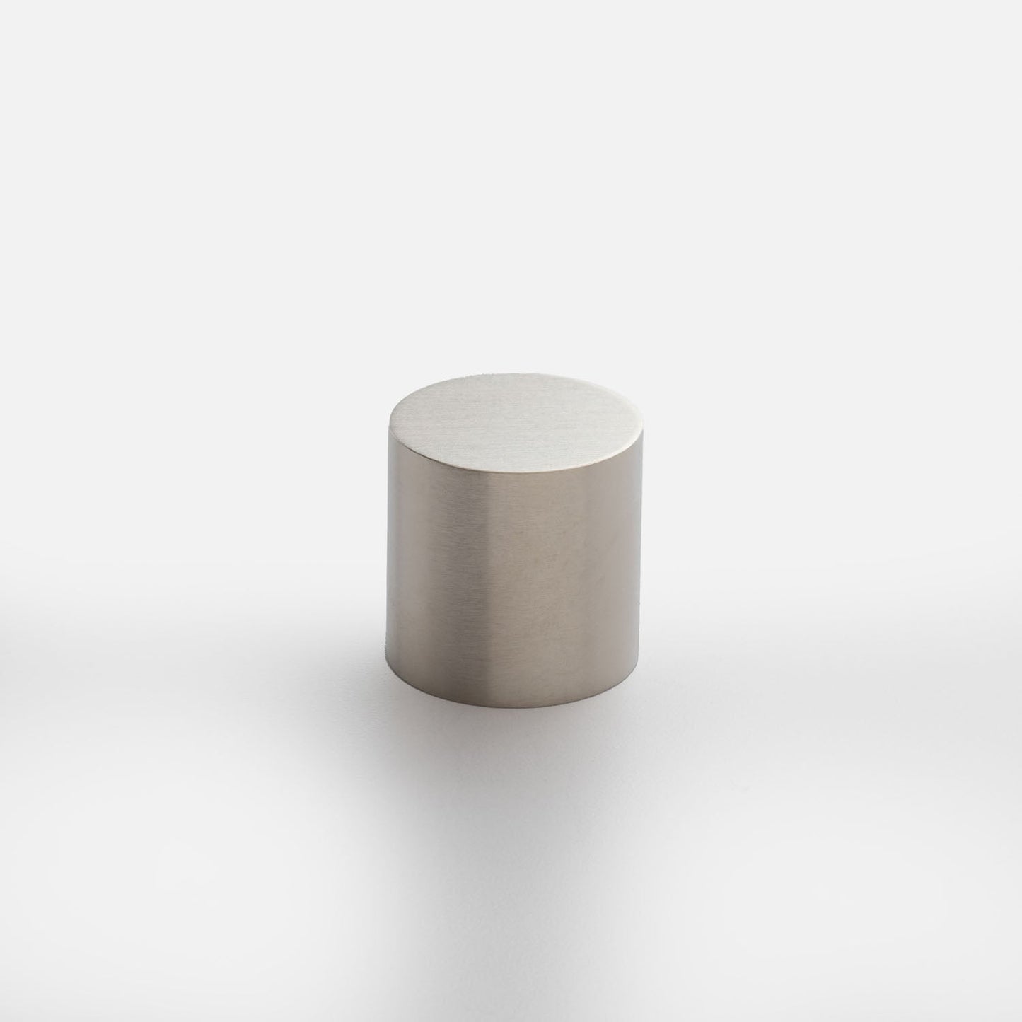 Front view of Cove Knob showcasing a cylindrical brushed metal design with a light gray background