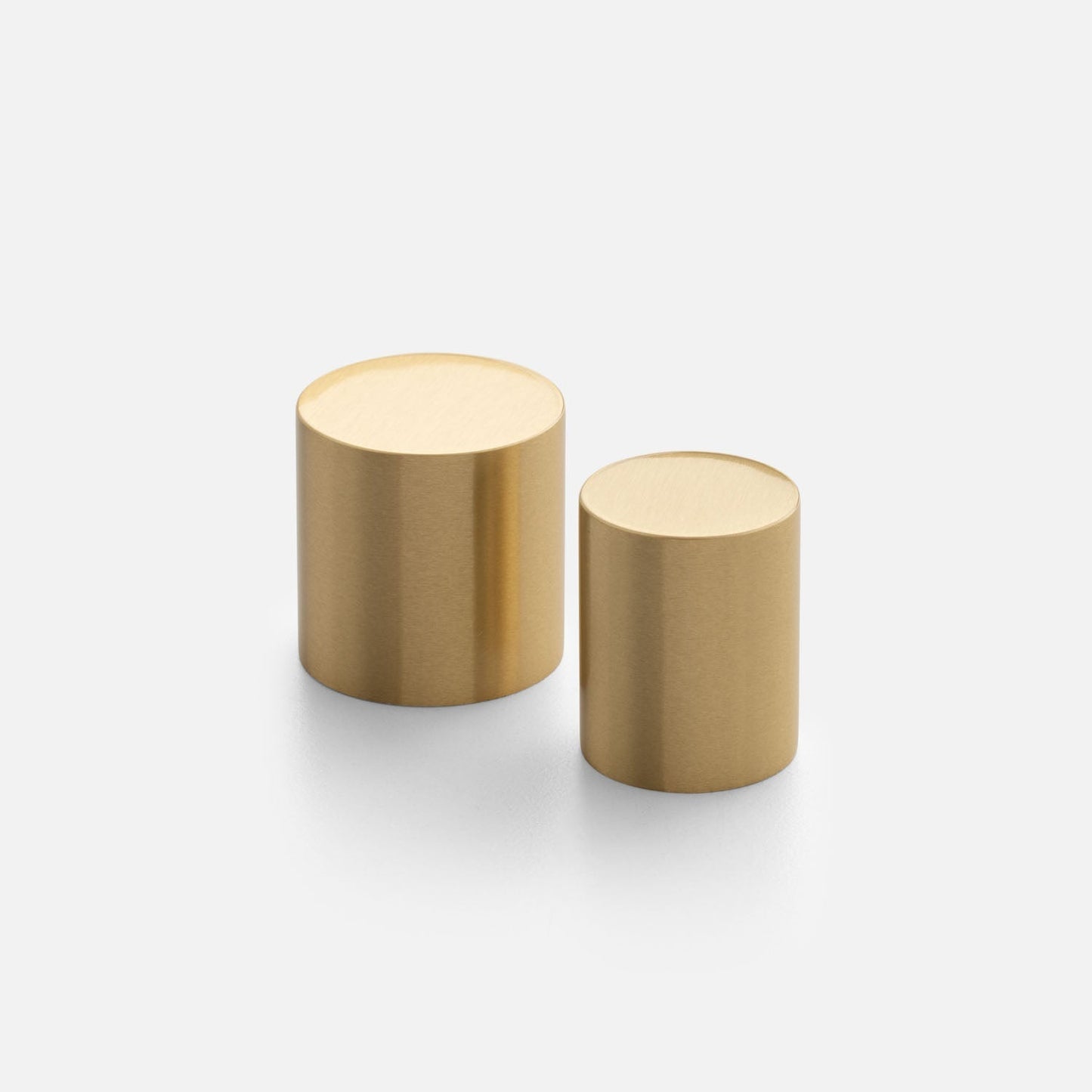 Angled view of two Cove Knobs showcasing cylindrical gold finishes on a white background