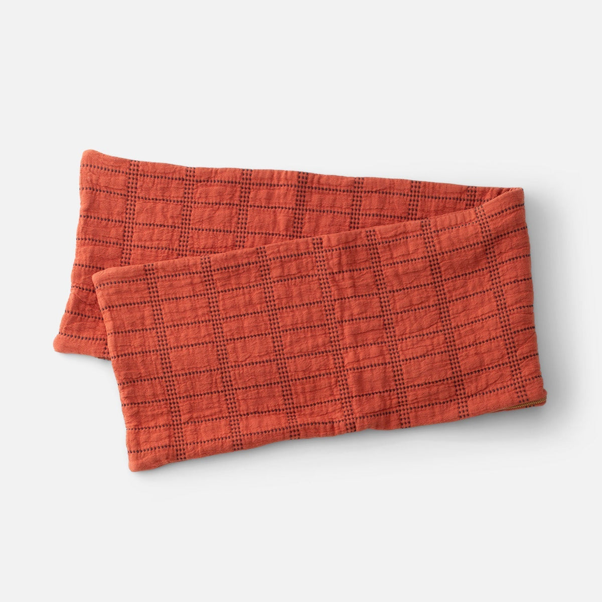 Angled view of Grid Stitch Pillow Cover showcasing a rust-colored textured grid pattern with a white background
