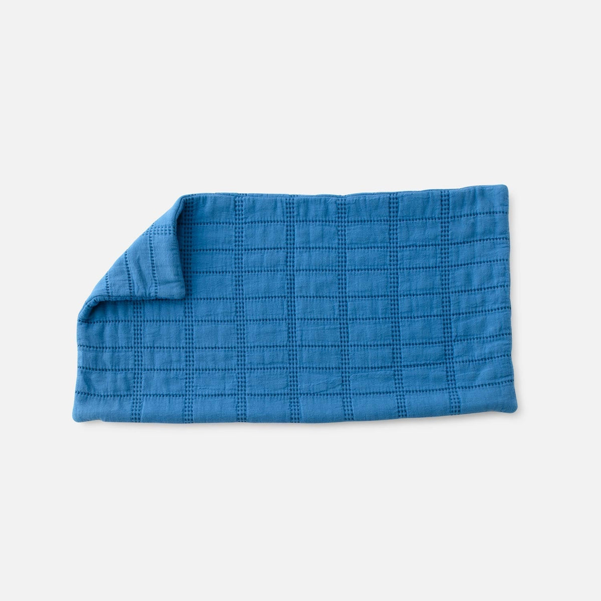 Front view of Grid Stitch Pillow Cover showcasing blue grid stitching and a folded corner on a light gray background