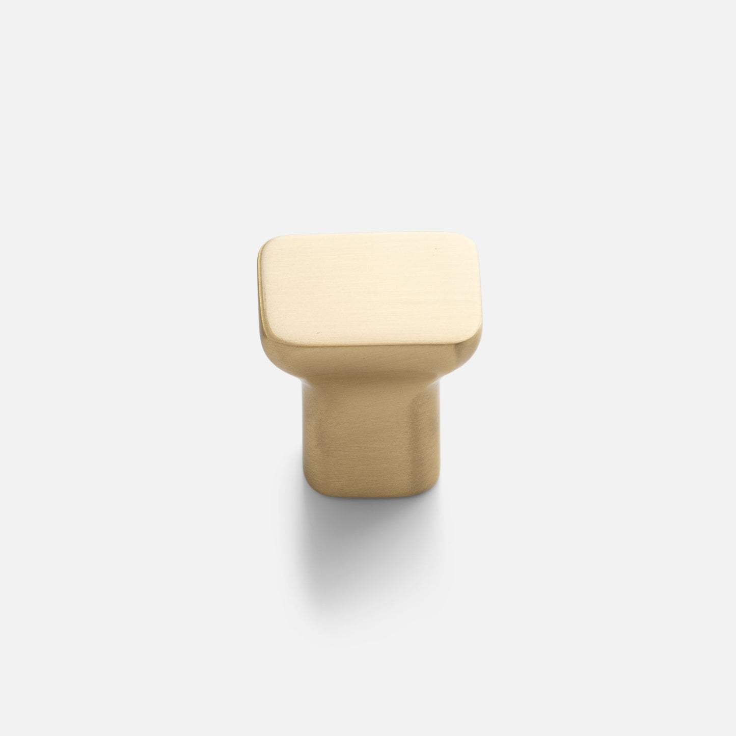 Close-up view of Cascade Knob showcasing its sloping organic silhouette in natural brass on a light background