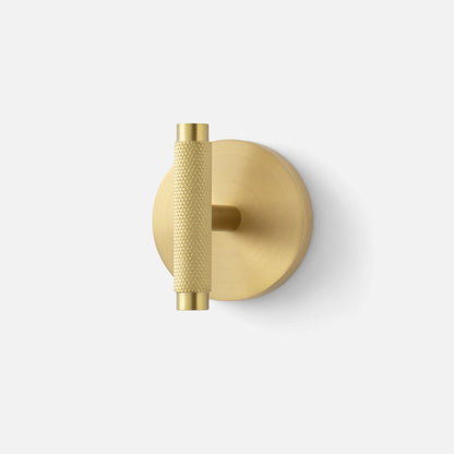 Front view of Knurled Hook showcasing cross-hatched natural brass grip and round mounting plate with a light gray background