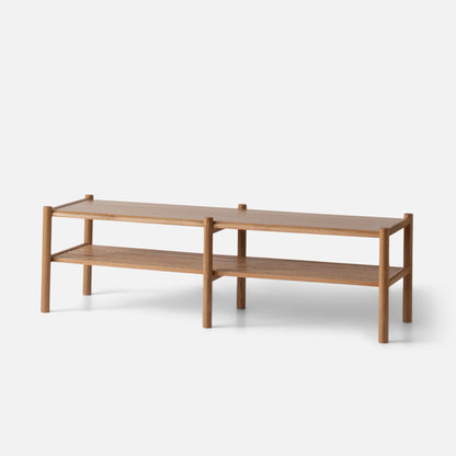 Three-quarter view of Nora Storage Bench showcasing oak construction, rounded wood legs, and lower shelf with white background