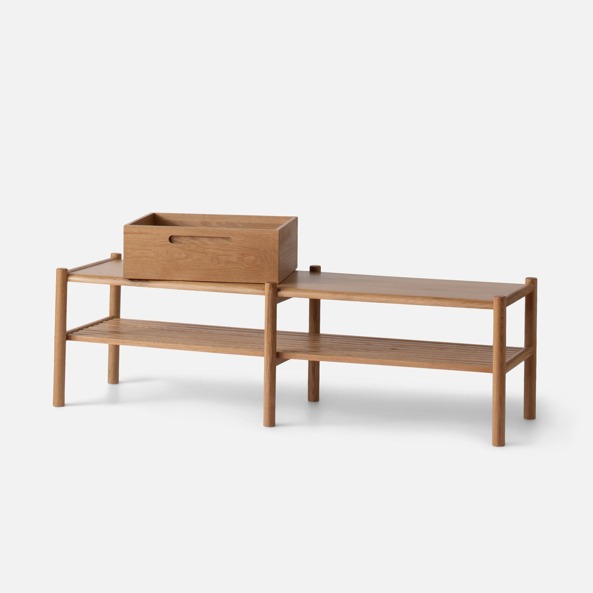 Three-quarter view of the Nora Storage Bench with oak wood, rounded legs, lower shelf, and removable box on white