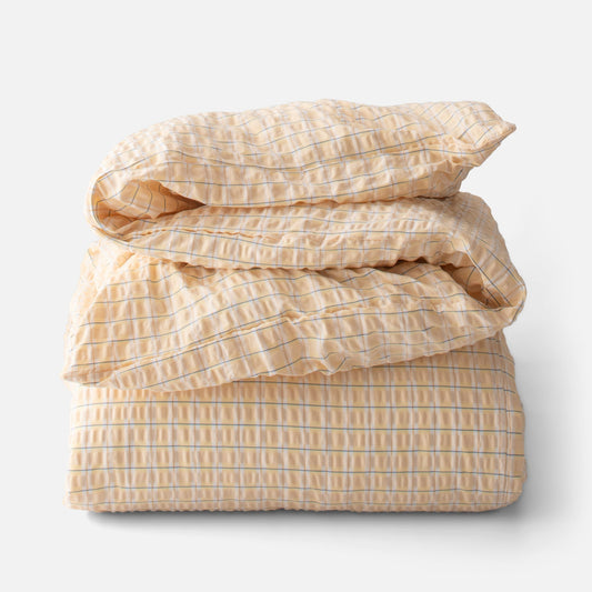 Folded view of Seersucker Check Duvet showcasing yellow and natural cotton seersucker with a check pattern on white