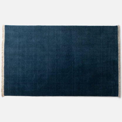 Top view of Mesa Wool Rug in green showcasing hand-loomed cut pile and natural fringe on a white background