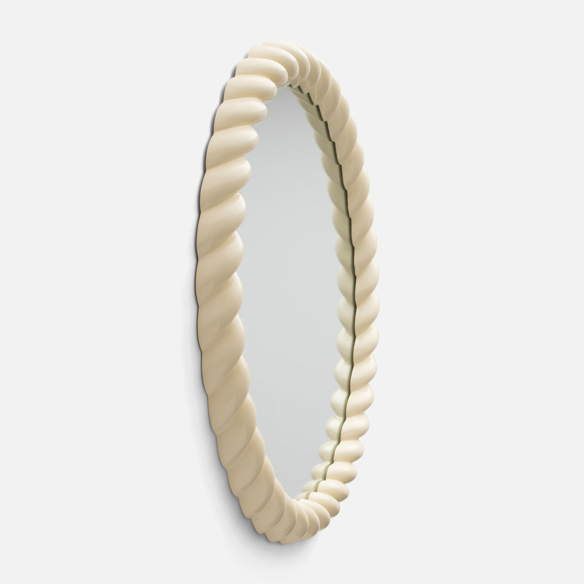 Angled view of Fernand Mirror showcasing its chunky twisted ecru-gloss frame against a light background
