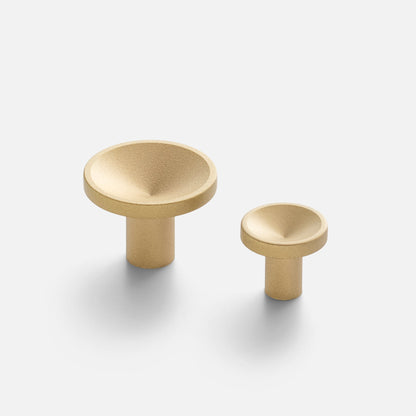 Angled view of two Rhone Cast Brass Knobs showcasing minimalist textured shapes on a white background