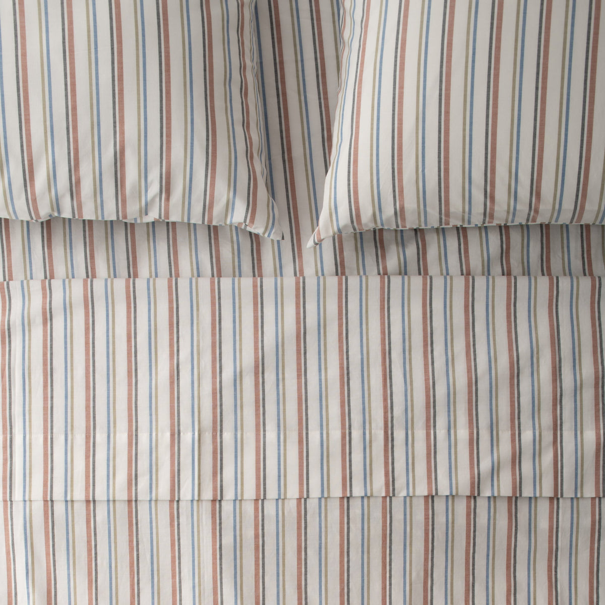 Close-up of Fresh Stripe Sheet Set showcasing classic tawny, olive, indigo, and black stripes on a bed