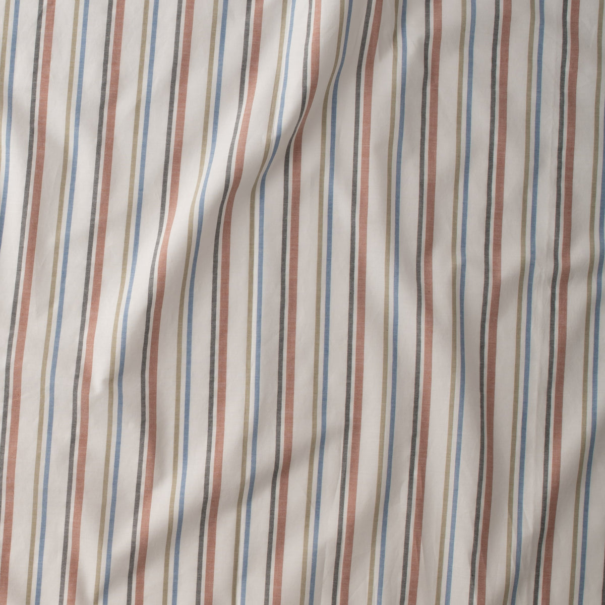 Close-up of Fresh Stripe Sheet Set in white showcasing tawny, olive, indigo, and black stripes on cotton fabric