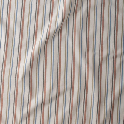 Close-up of Fresh Stripe Sheet Set in white showcasing tawny, olive, indigo, and black stripes on cotton fabric