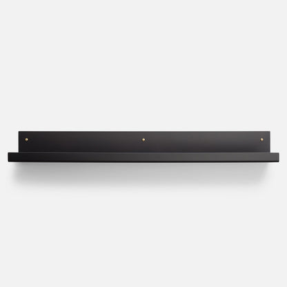 Front view of Brake Angle Picture Ledge showcasing black satin steel shelf and brass mounting hardware on a light background
