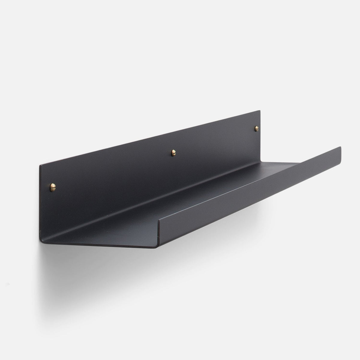 Angled front view of Brake Angle Picture Ledge showcasing black satin steel construction and natural brass mounting hardware against a white background