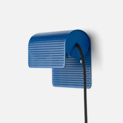 Angled view of Swell Plug-In Sconce showcasing its Cobalt-Satin perforated metal shade and black cord against a light background