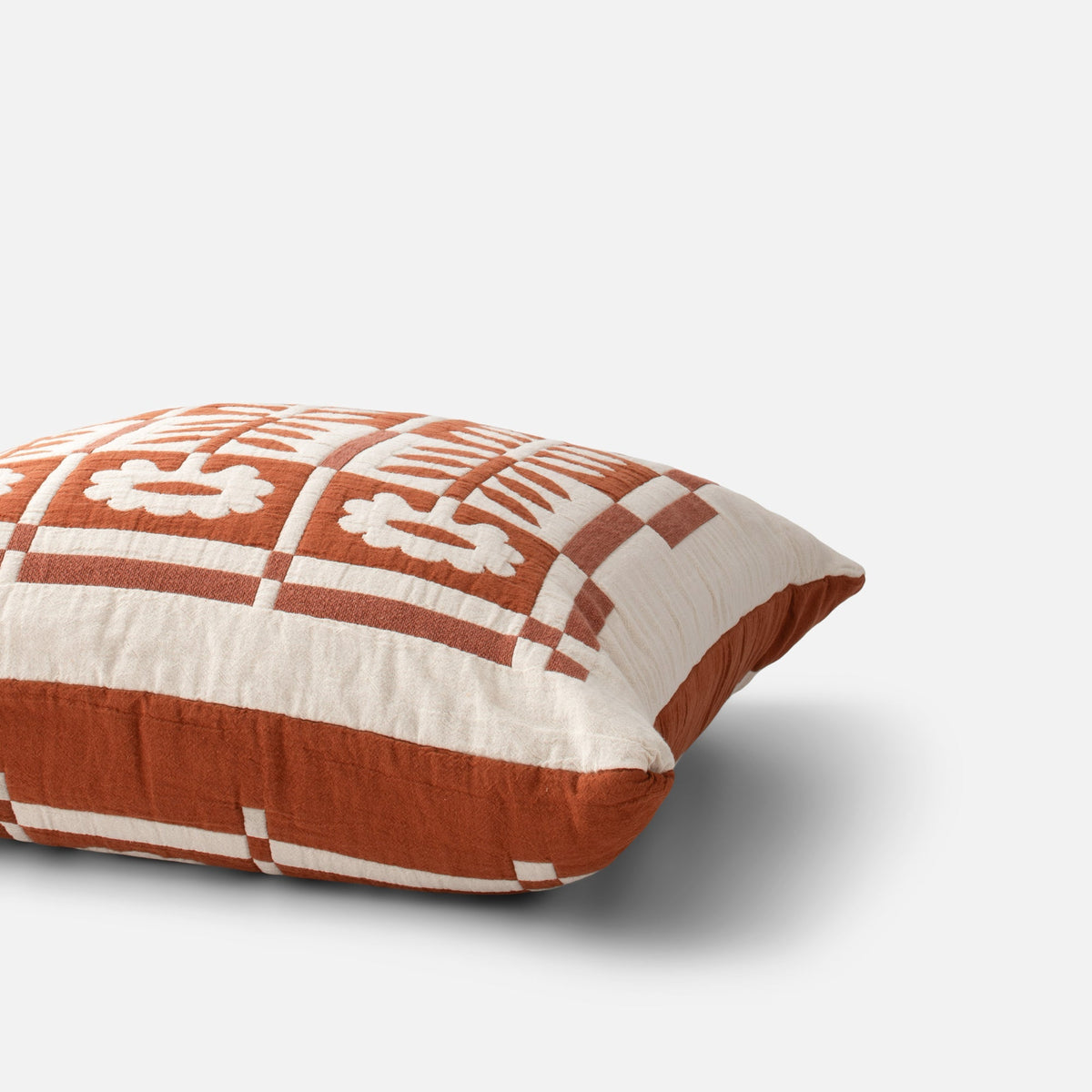 Close-up view of the Stillwater Sham showcasing a rust and cream checked pattern with floral motifs on a white background