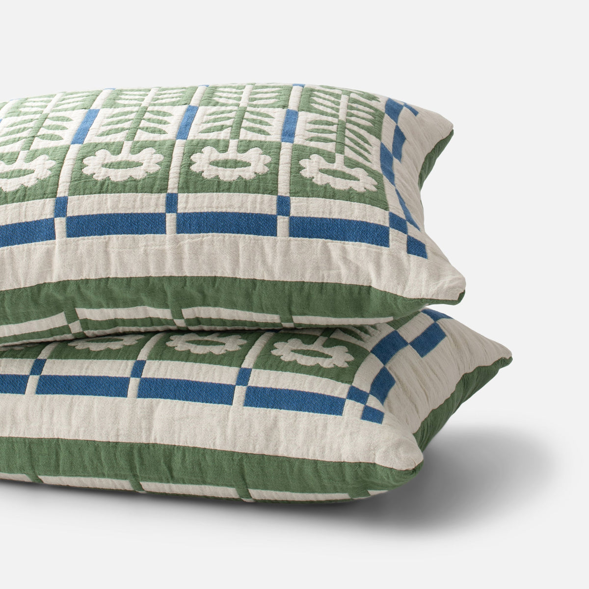 Close-up view of Stillwater Sham showcasing green, blue, and cream geometric pattern on white background