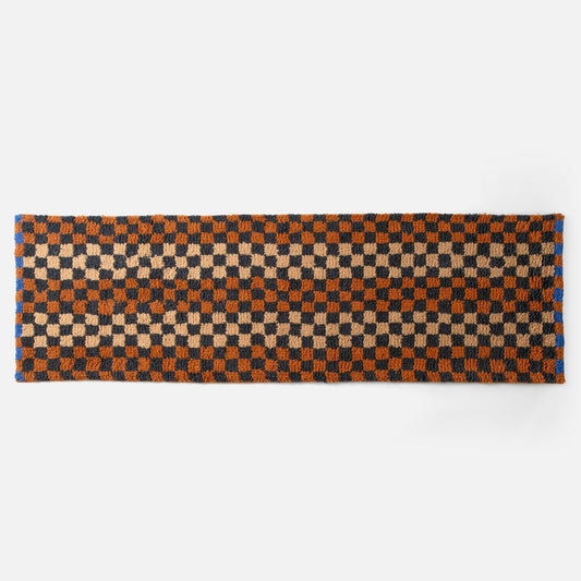 Top edge view of Felix shag wool rug showcasing butterscotch and navy checkerboard pattern and high-pile texture on white background