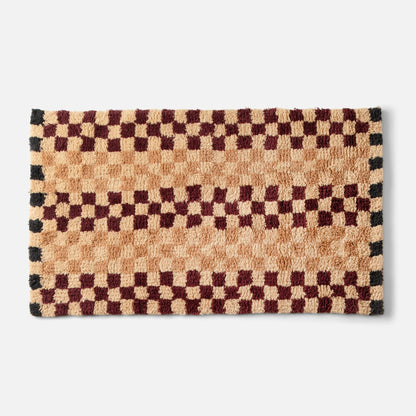 Top-edge close-up of Felix Shag Wool Rug showing butterscotch and burgundy checkerboard high-pile wool on white background