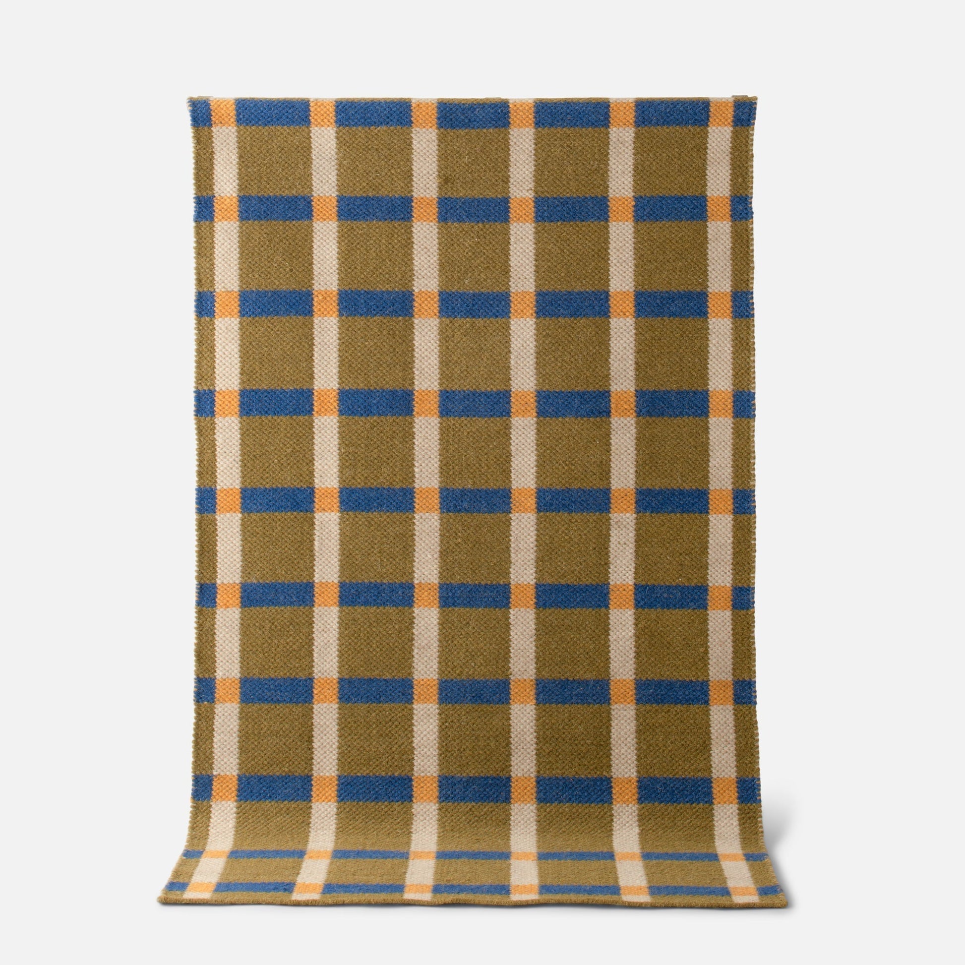 Top-down view of Plaid Wool Reversible Rug showing blue and orange plaid on olive and cream wool on white background