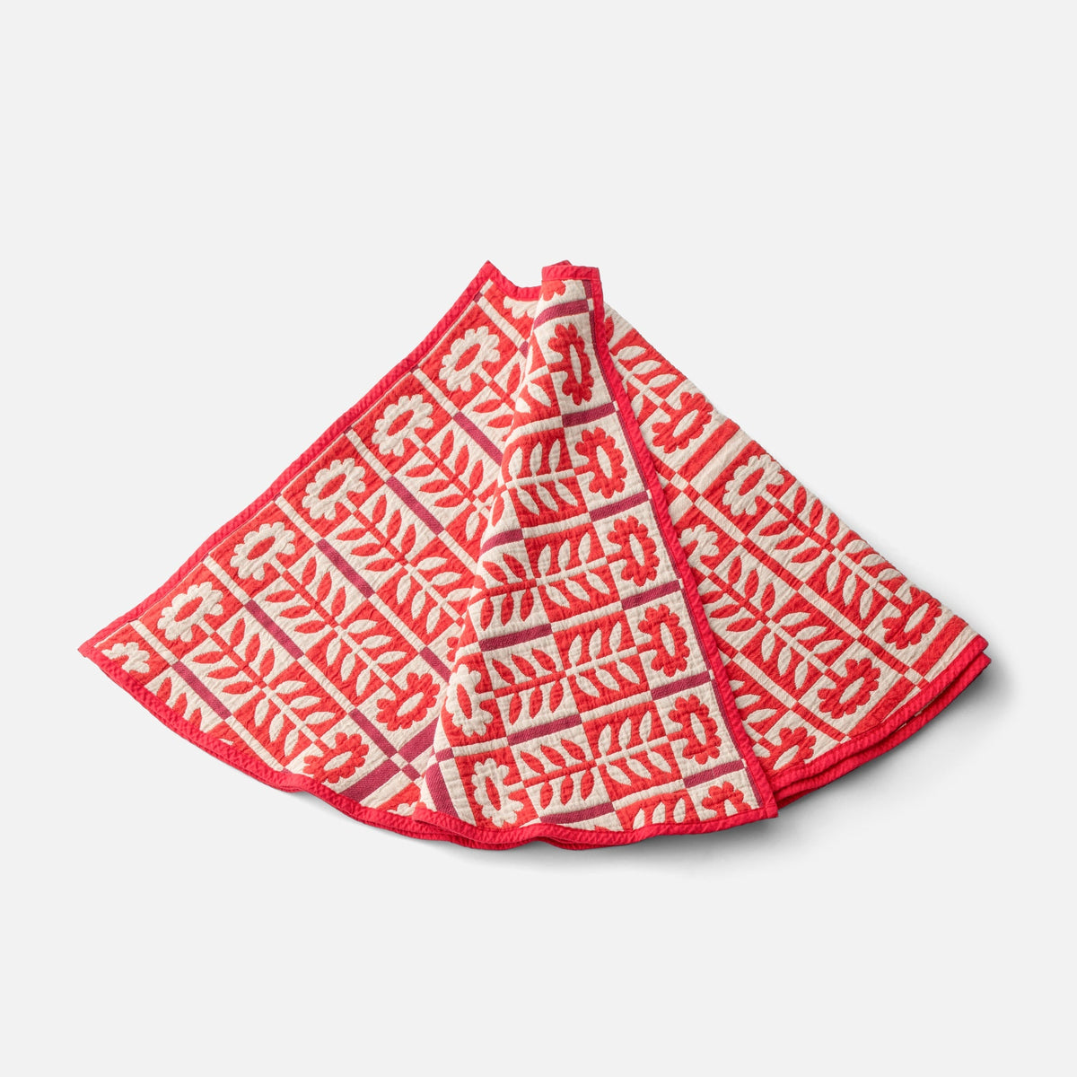 Angled view of the red Stillwater Tree Skirt showcasing its mirrored floral jacquard pattern on a white background
