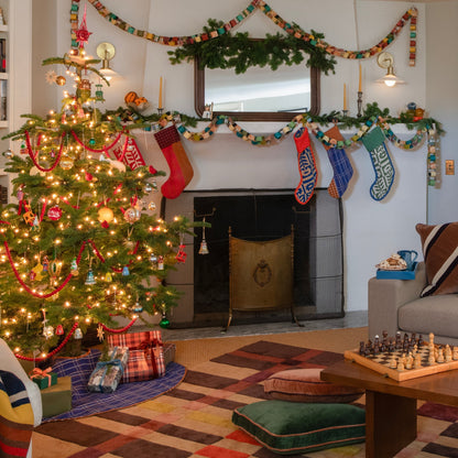 Holiday living room decorated with a Christmas tree, fireplace, garlands, and colorful stockings