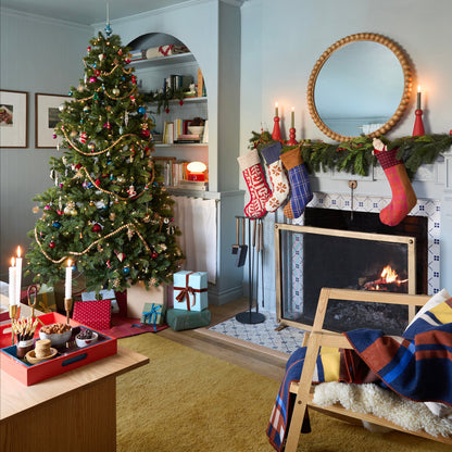 Festive living room with a decorated Christmas tree, fireplace, and red Swiss Scallop Stocking on the mantel