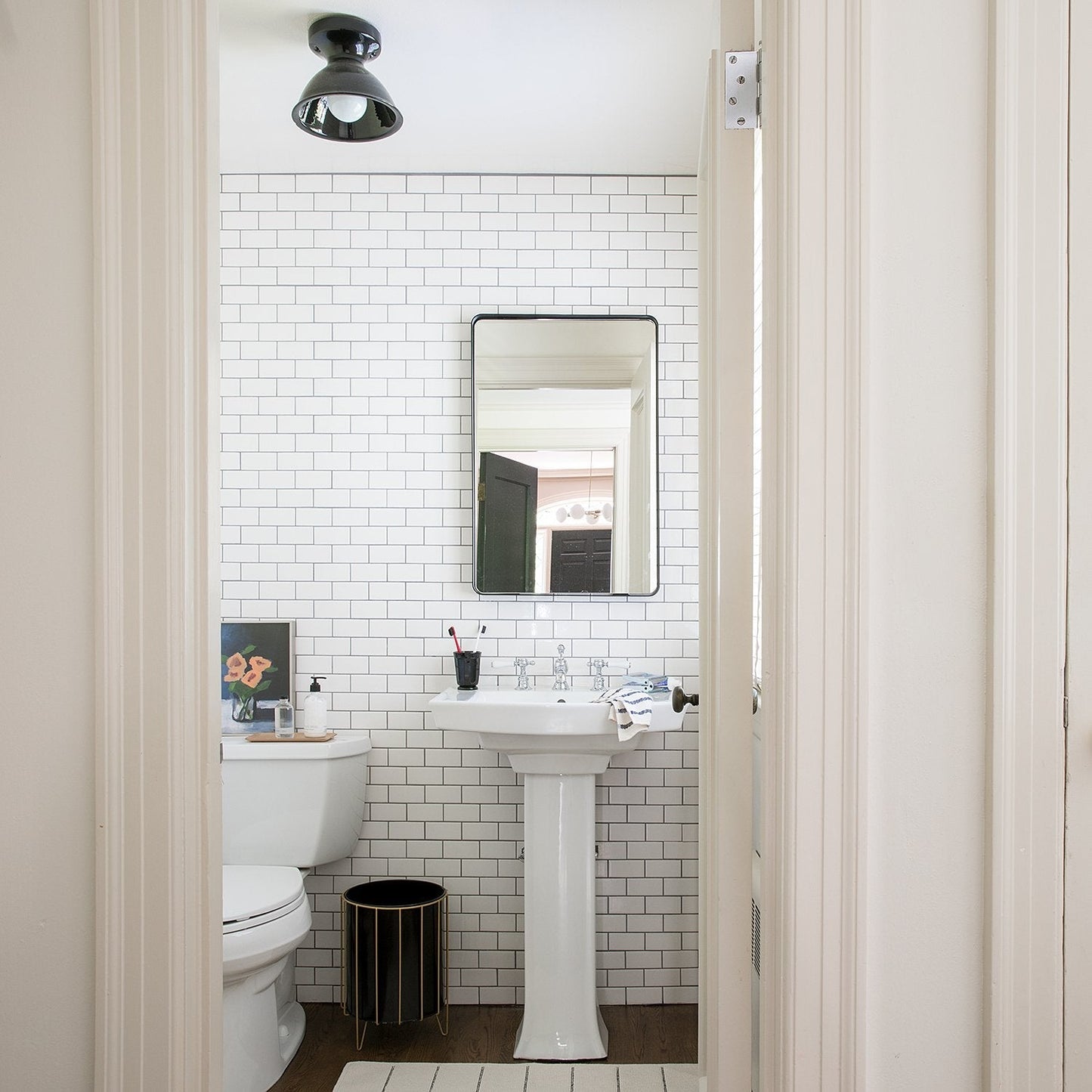 Front view of Leo Mirror showcasing thin black metal frame with rounded corners against a white subway-tiled bathroom wall