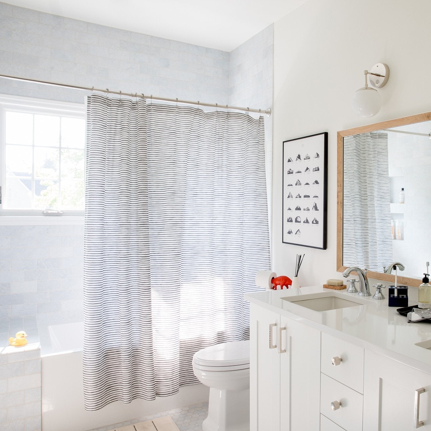 Edgecliff Pulls installed on a white bathroom vanity beside a striped shower curtain