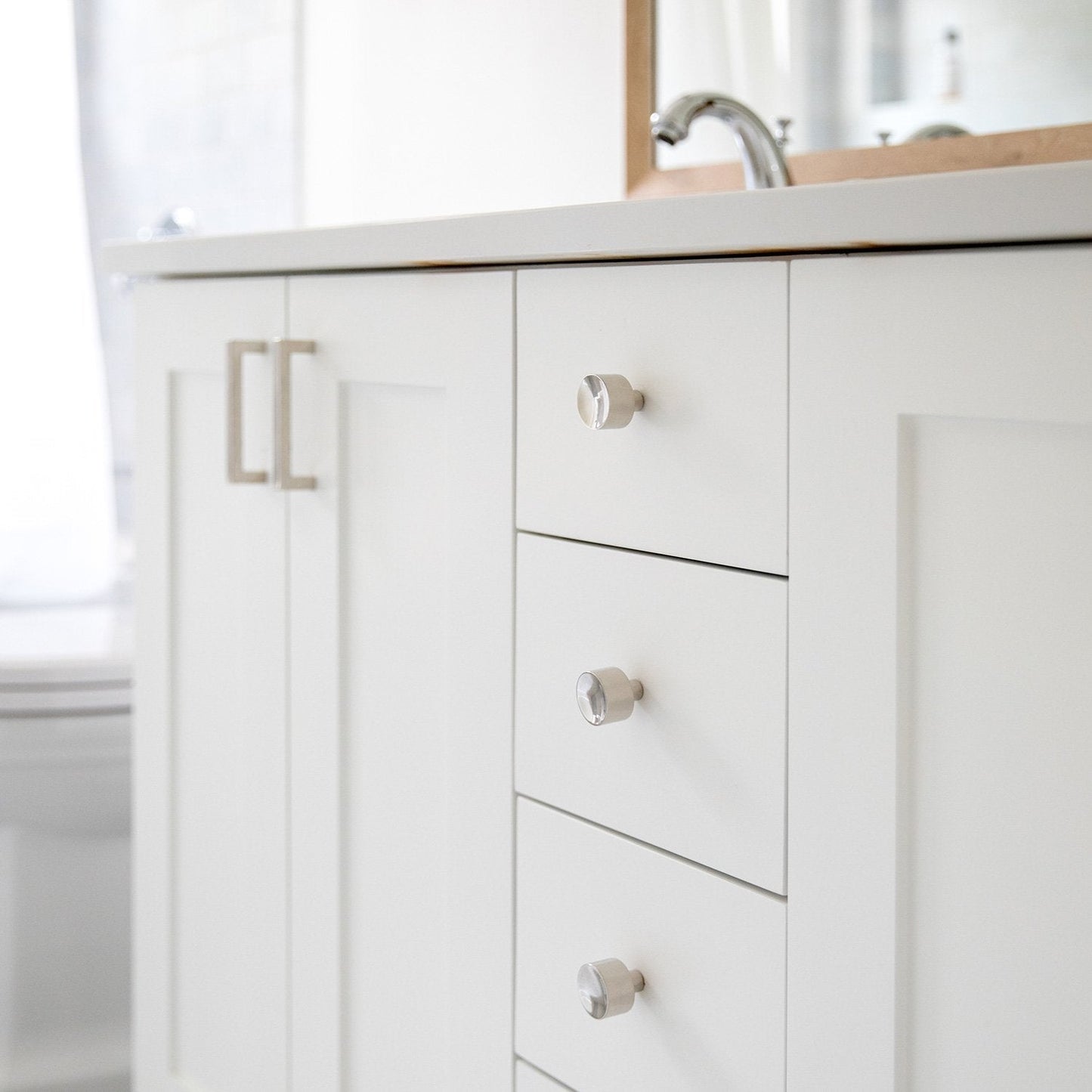Front view of Edgecliff Pull showcasing a cylindrical white finish and clear faceted face on a bathroom vanity