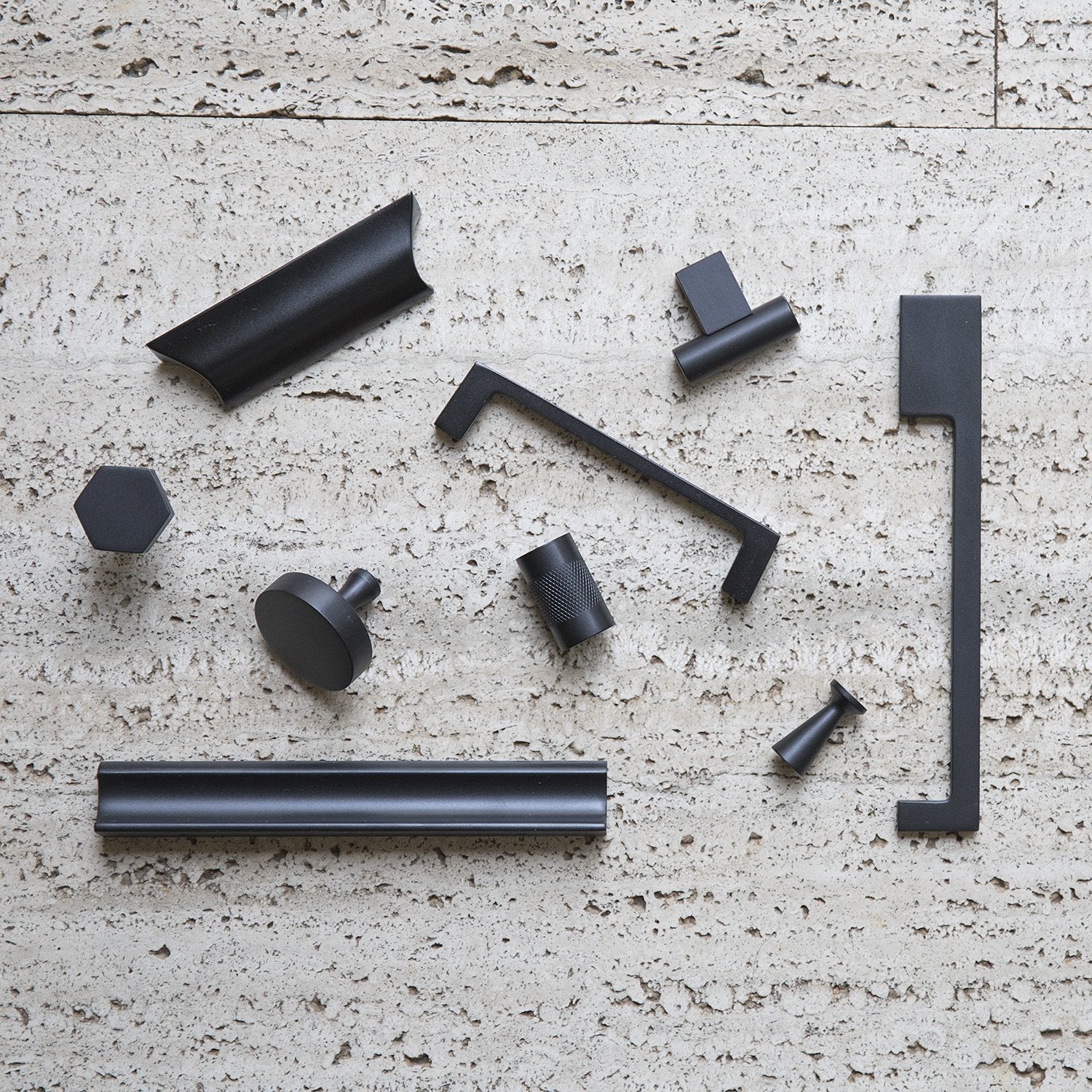 Overhead view of the True Black Radcliffe Knob showcasing solid brass construction with coordinating hardware on a textured stone surface