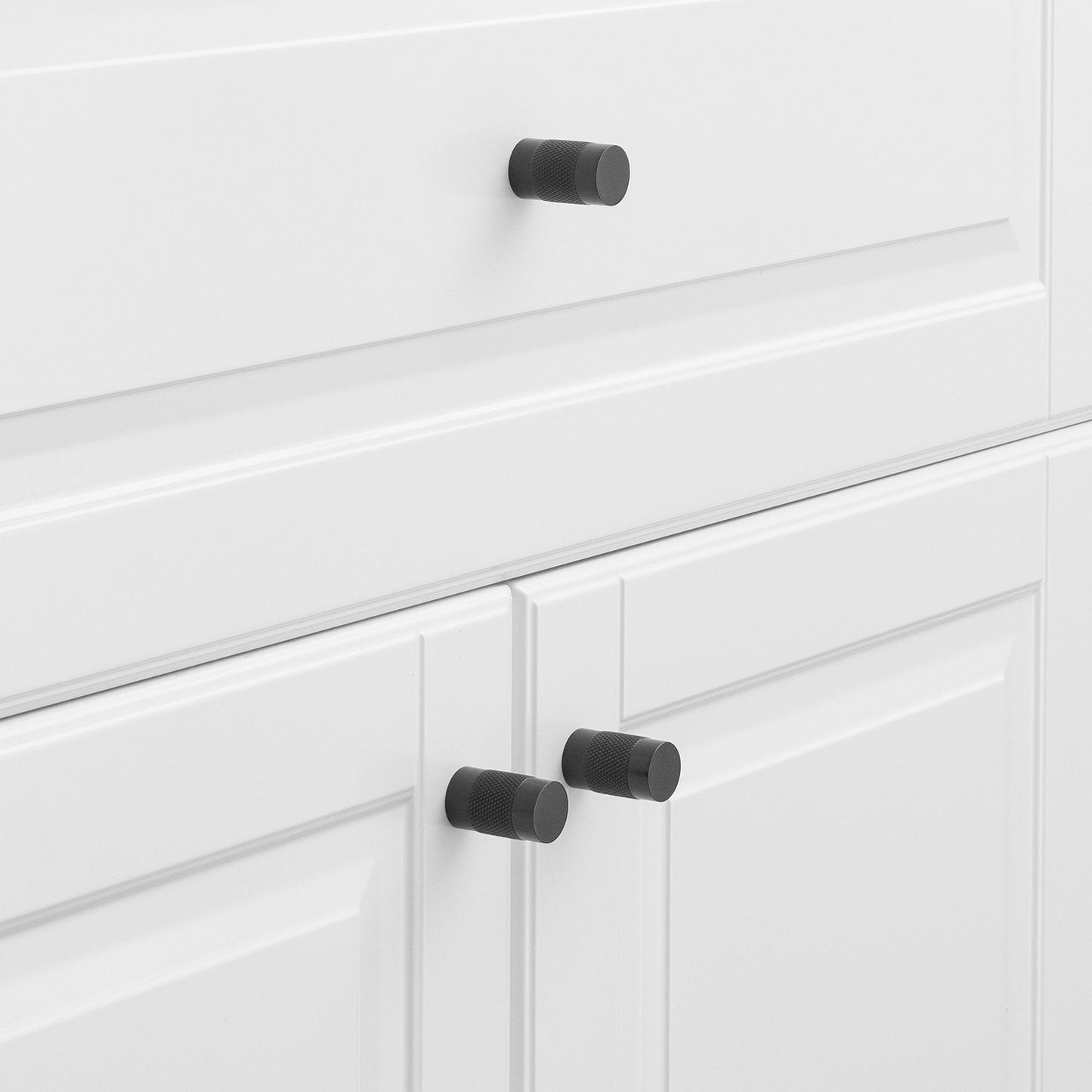 Black knurled knobs installed on white cabinet doors