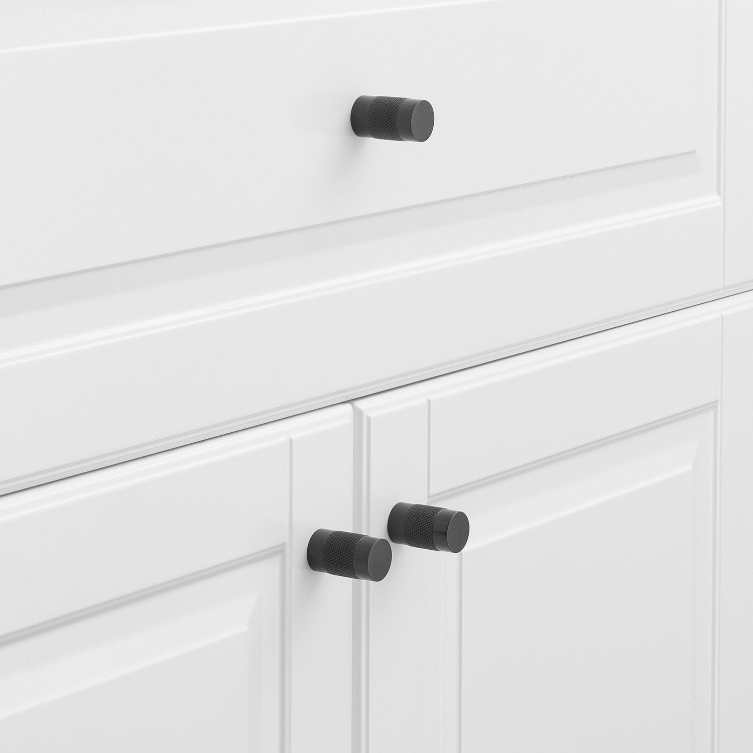 Black knurled knobs installed on white cabinet doors