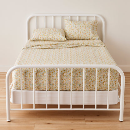 Front view of Wallowa Floral Percale Sheet Set showing small yellow floral print on 100% cotton percale on a white metal bed frame