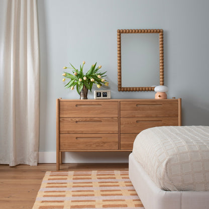 Front view of Nora 6-Drawer Dresser showcasing six drawers and pill-shaped handles with a bedroom background