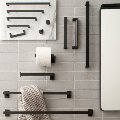 Black Edgecliff pulls and bathroom hardware displayed on a gray brick wall beside a mirror