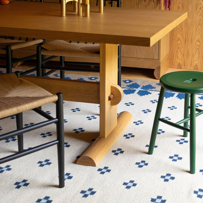 Close-up view of Darrow Dining Table showcasing solid oak frame and walnut stretcher with chairs and patterned rug