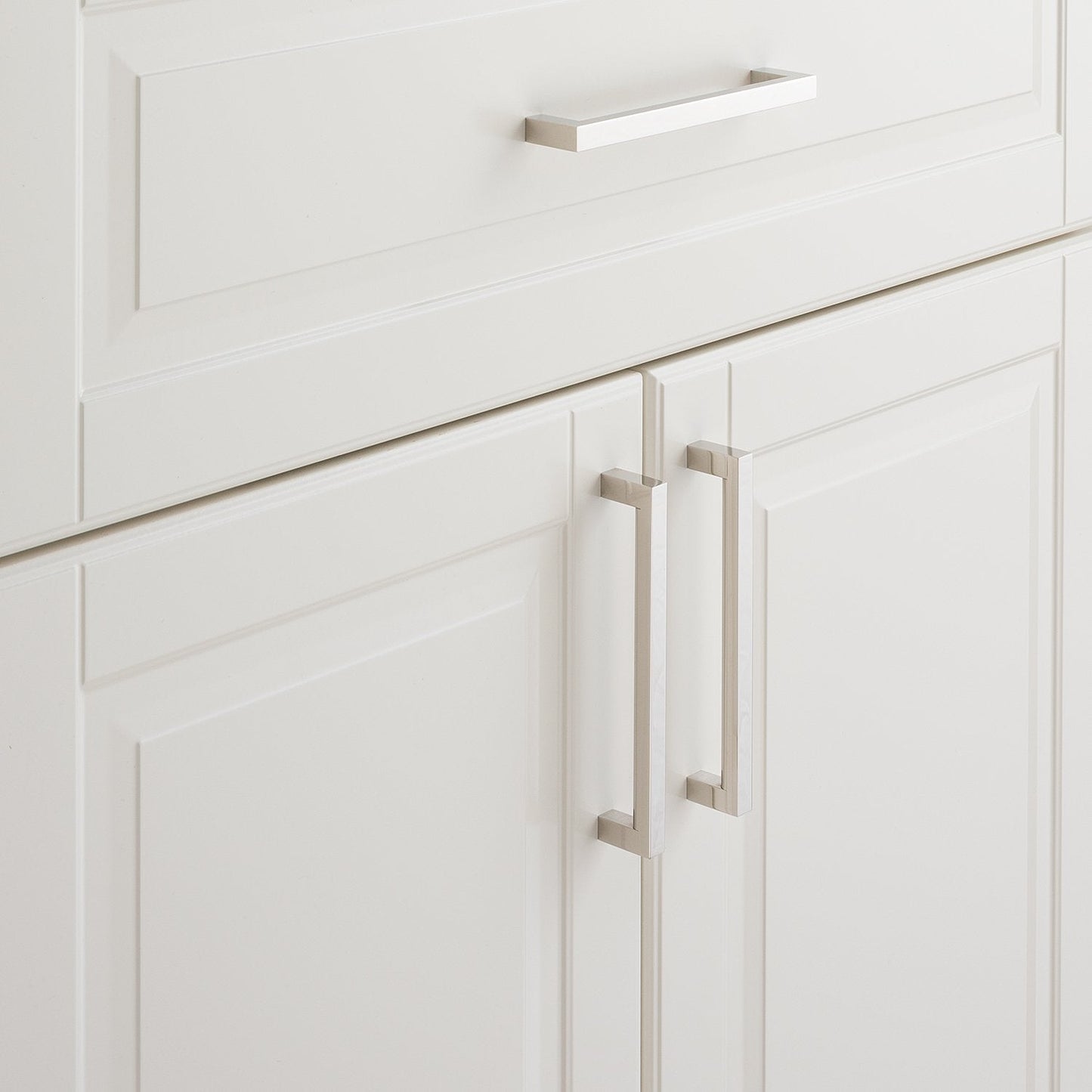 Close-up of Edgecliff Pull showcasing long rectangular hardware on white paneled cabinets